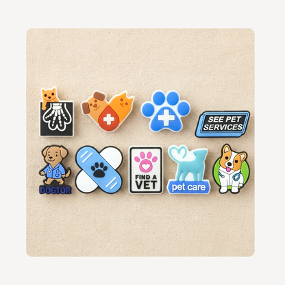 Eight colorful pet-themed clog charms arranged in two rows on a beige textured square background. The pins feature veterinary and pet care motifs including a cat X-ray, hearts, a blue paw print, a 'SEE PET SERVICES' sign, a dog labeled 'DOCTOR', a bandage, a 'FIND A VET' sign, a light blue dog silhouette, and a corgi with a stethoscope.