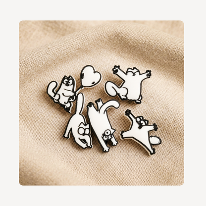 Five white cartoon cat clog charms with black outlines, arranged on a beige textured fabric background.