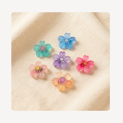 Six small translucent flower-shaped clog charms in pastel colors including teal, blue, pink, purple, peach, and coral, arranged on a soft beige fabric background.