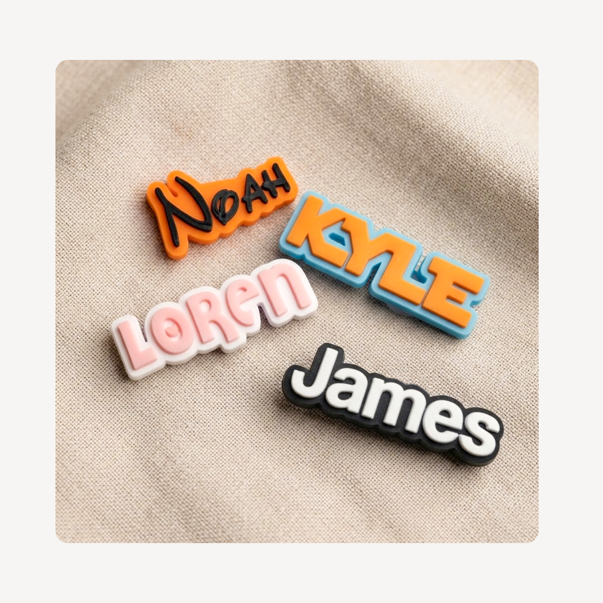 Four personalized name clog charms spelling Noah, Kyle, Loren, and James, displayed on a textured beige fabric background.