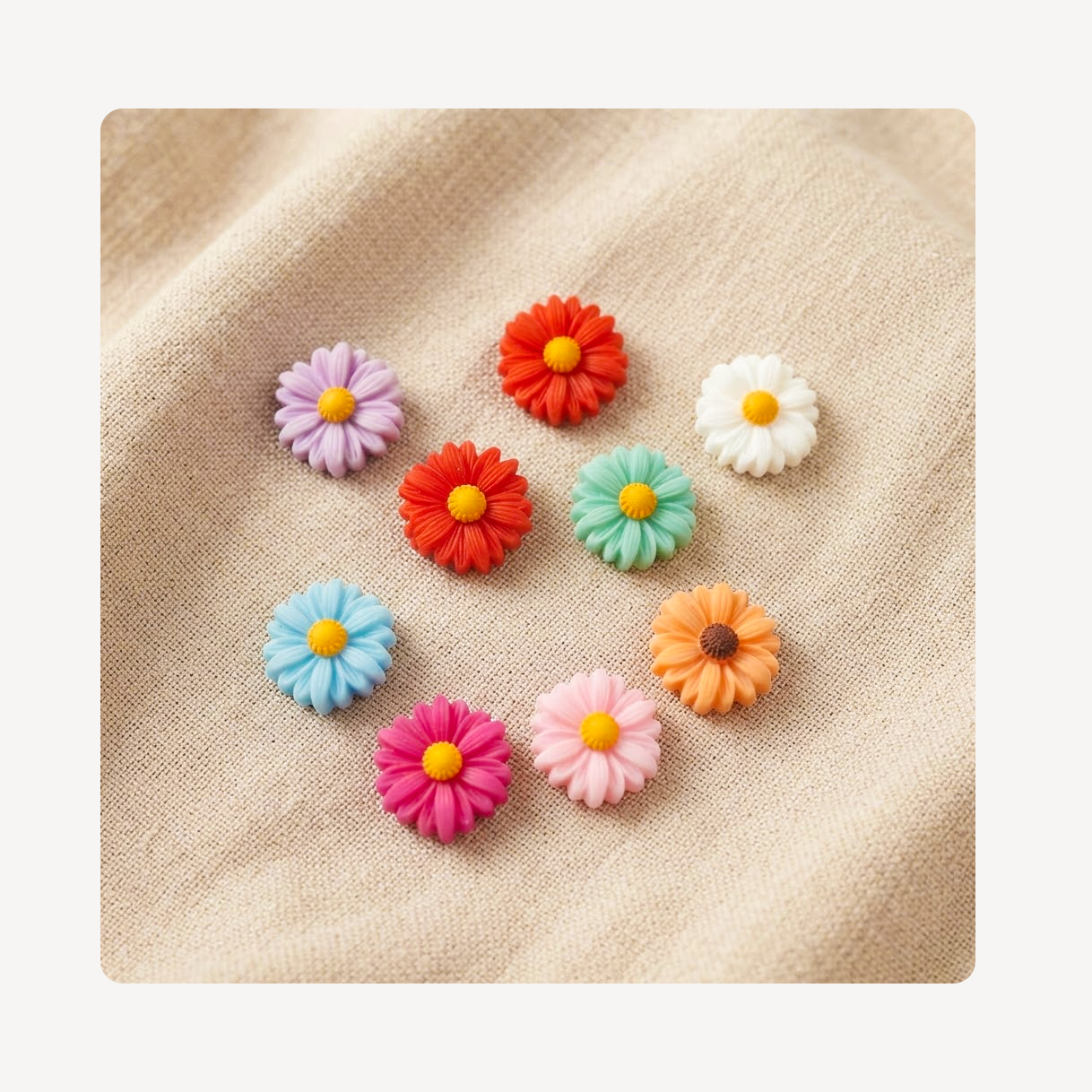 Nine colorful daisy-shaped craft clog charms or beads with yellow centers, arranged on a textured beige linen fabric background.