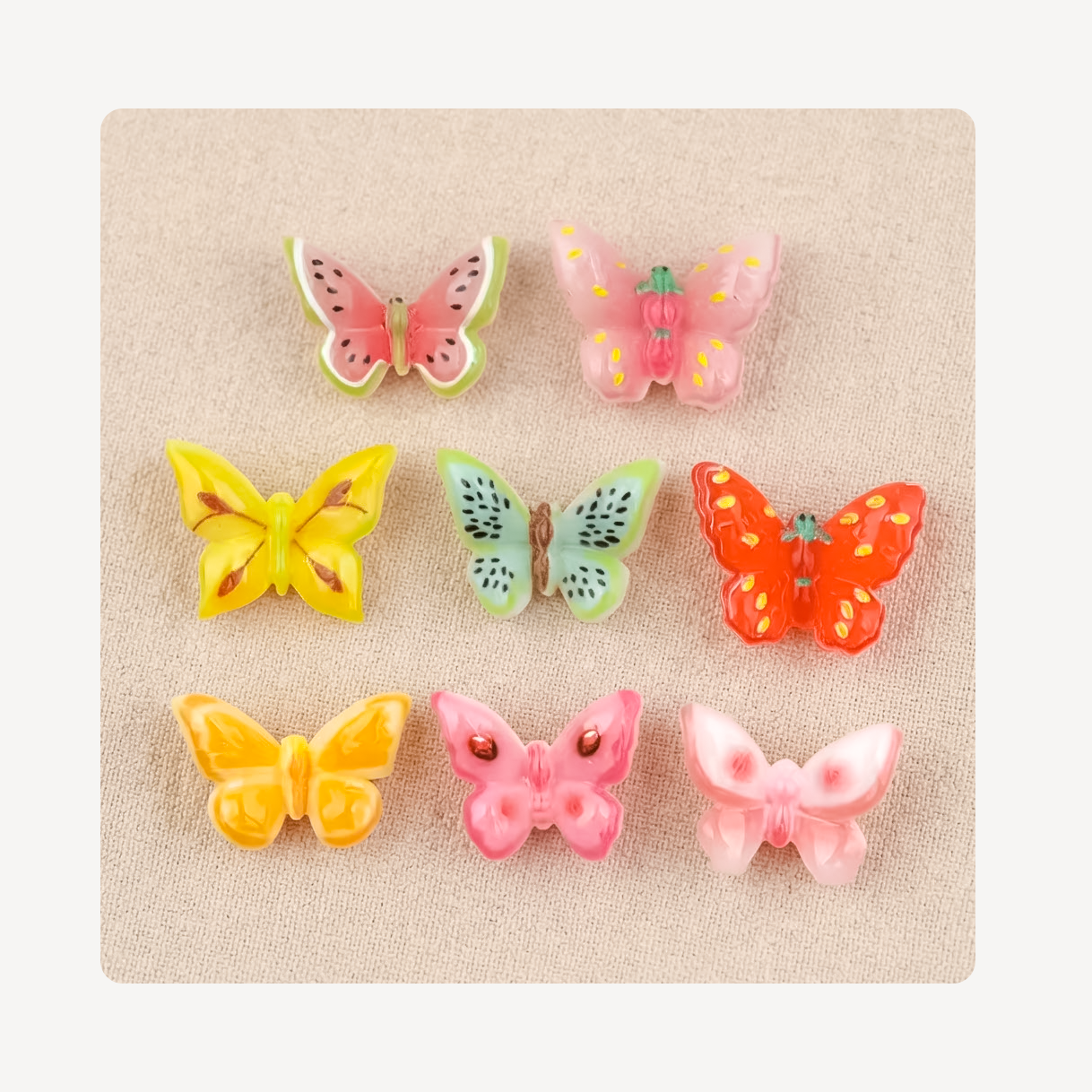 Six colorful butterfly-shaped clog charms arranged in a 3-by-2 grid on a textured beige fabric background.
