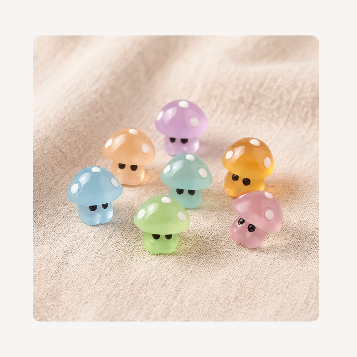 Seven small glossy mushroom-shaped clog charms in pastel colors, including blue, peach, purple, yellow, mint, green, and pink, arranged on a soft beige fabric background.