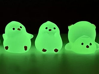 A set of glow in the dark chickens or chicks around a campfire shoe charms on a pair of shoes shoes. The chicks all have unique positions.