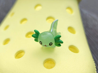 Colorful axolotl charms on a pair of yellow shoes shoes. The axolotls are blue, purple, green, orange, yellow and pink and have cute, smiling faces.