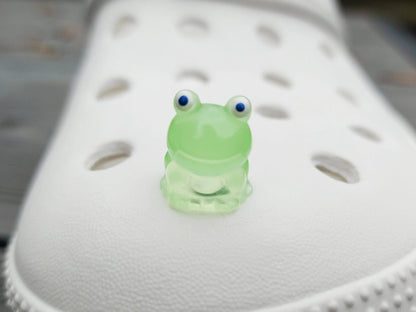 Glow-in-the-dark frog charms on a shoe shoe. These playful and luminous accessories add a fun, froggy touch to your footwear, making them perfect for customizing your shoes with a whimsical and adventurous vibe.