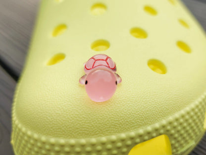 Glow-in-the-dark turtle charms on a shoe shoe. These adorable accessories, featuring detailed shell designs, bring a playful and luminous touch to the footwear, perfect for customizing your shoes with a fun, ocean-inspired look.