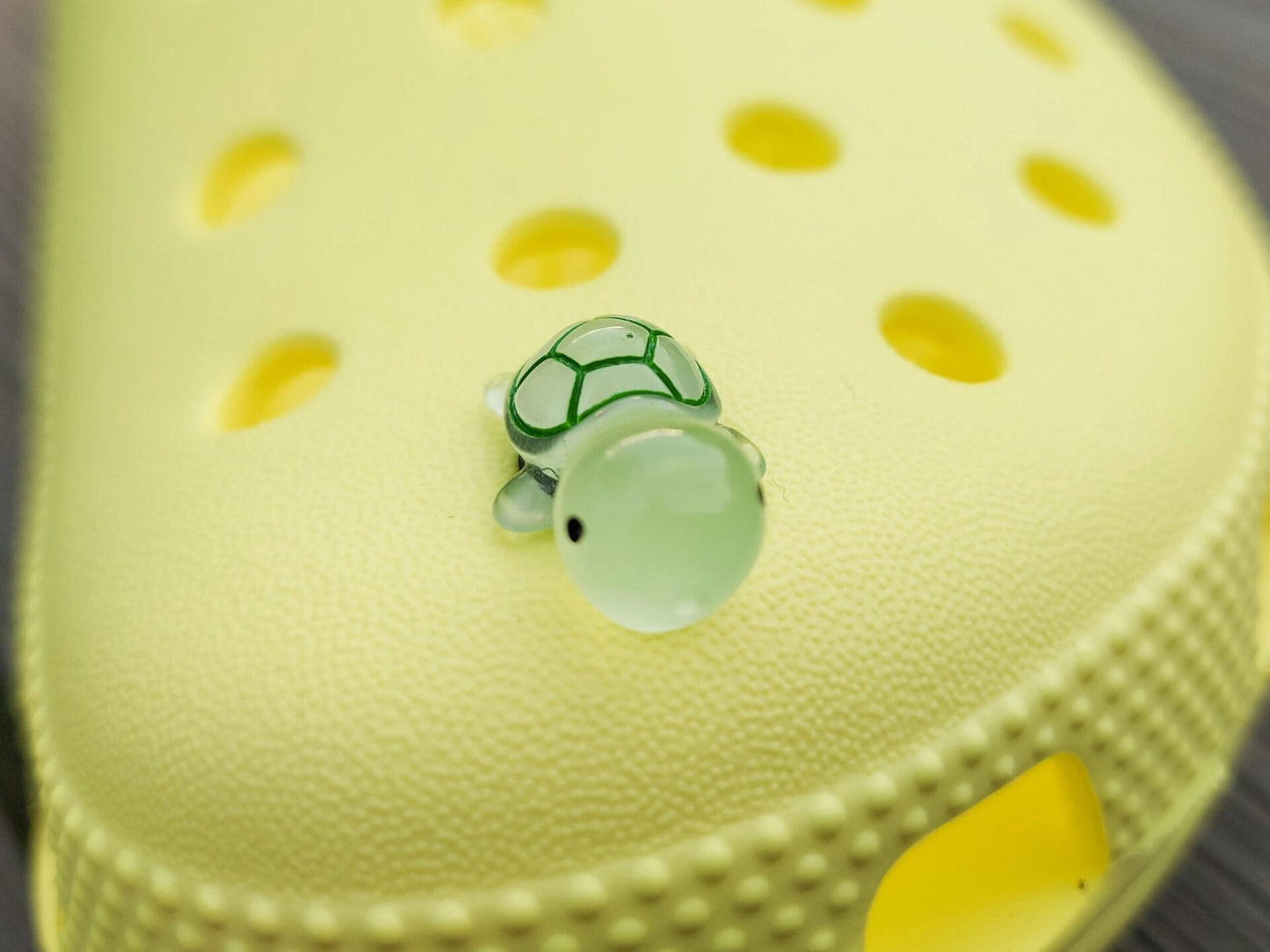 Glow-in-the-dark turtle charms on a shoe shoe. These adorable accessories, featuring detailed shell designs, bring a playful and luminous touch to the footwear, perfect for customizing your shoes with a fun, ocean-inspired look.
