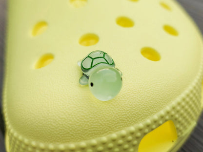 Glow-in-the-dark turtle charms on a shoe shoe. These adorable accessories, featuring detailed shell designs, bring a playful and luminous touch to the footwear, perfect for customizing your shoes with a fun, ocean-inspired look.
