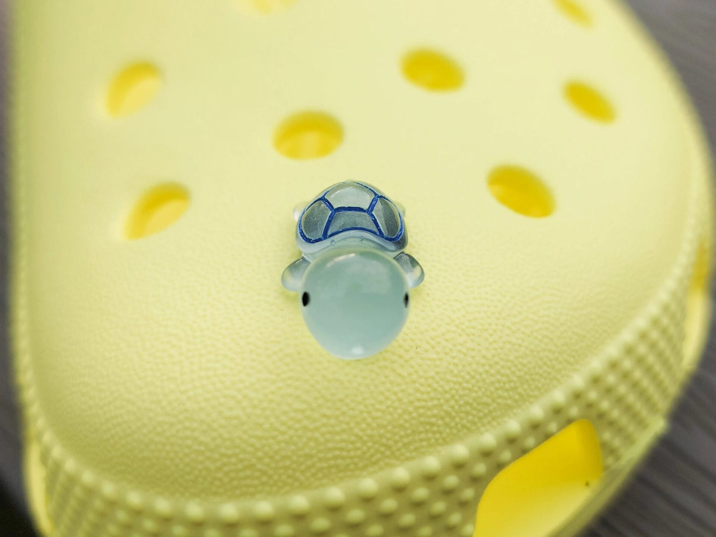 Glow-in-the-dark turtle charms on a shoe shoe. These adorable accessories, featuring detailed shell designs, bring a playful and luminous touch to the footwear, perfect for customizing your shoes with a fun, ocean-inspired look.