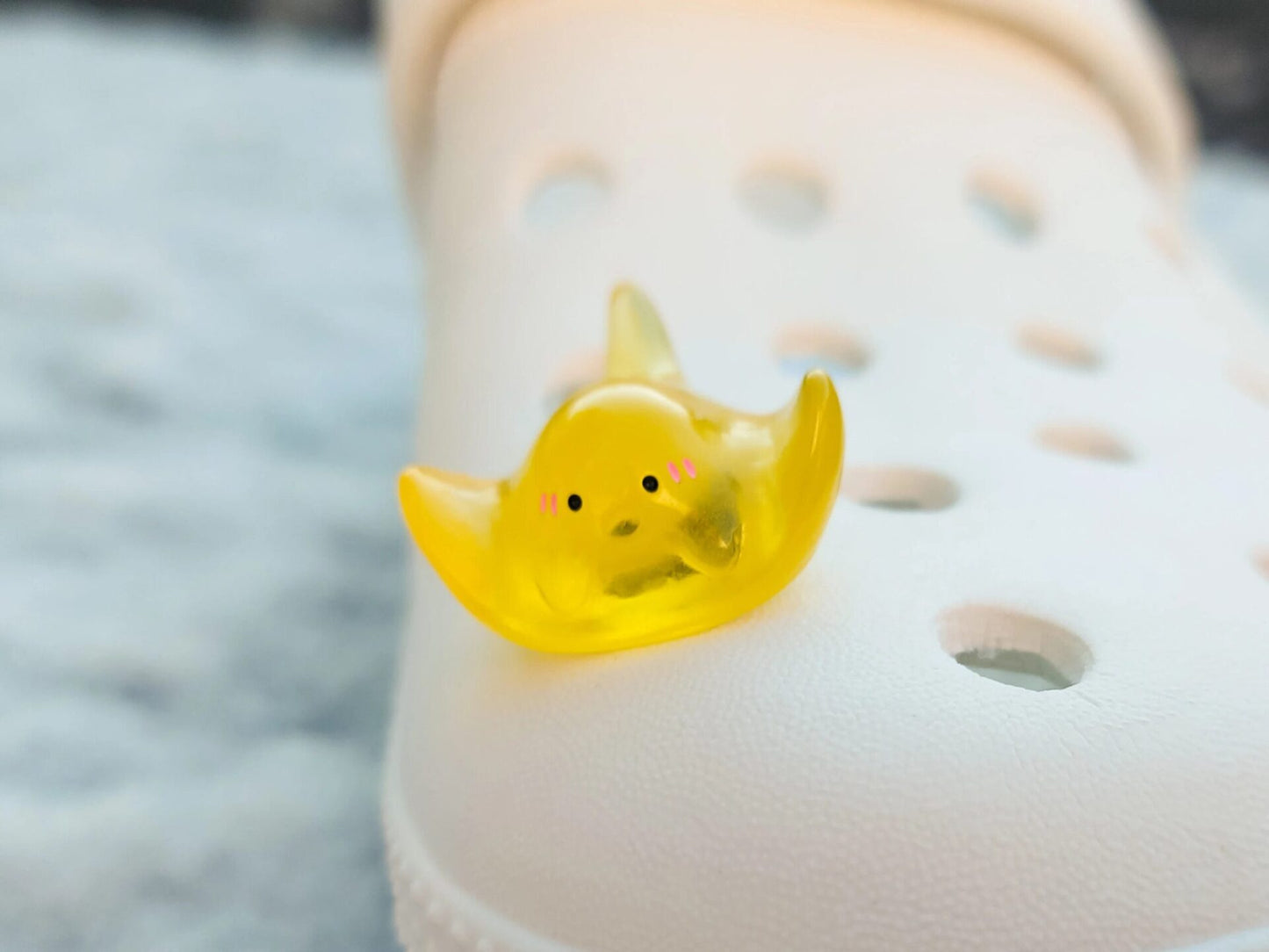 Glow-in-the-dark manta ray charms on a shoe shoe. These enchanting accessories light up in the dark, adding a marine-inspired touch to your footwear. Perfect for customizing your shoes with a unique and magical ocean theme.