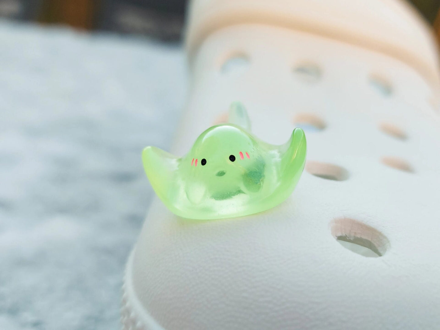Glow-in-the-dark manta ray charms on a shoe shoe. These enchanting accessories light up in the dark, adding a marine-inspired touch to your footwear. Perfect for customizing your shoes with a unique and magical ocean theme.