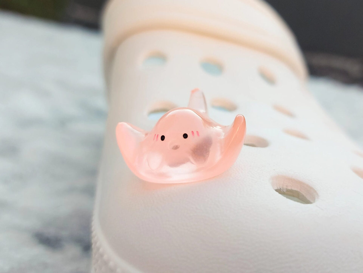 Glow-in-the-dark manta ray charms on a shoe shoe. These enchanting accessories light up in the dark, adding a marine-inspired touch to your footwear. Perfect for customizing your shoes with a unique and magical ocean theme.