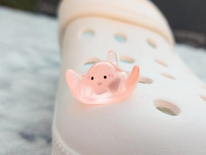 Glow-in-the-dark manta ray charms on a shoe shoe. These enchanting accessories light up in the dark, adding a marine-inspired touch to your footwear. Perfect for customizing your shoes with a unique and magical ocean theme.