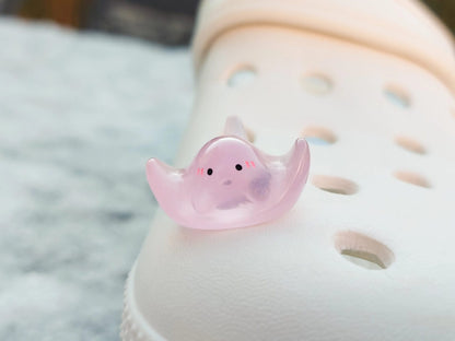 Glow-in-the-dark manta ray charms on a shoe shoe. These enchanting accessories light up in the dark, adding a marine-inspired touch to your footwear. Perfect for customizing your shoes with a unique and magical ocean theme.