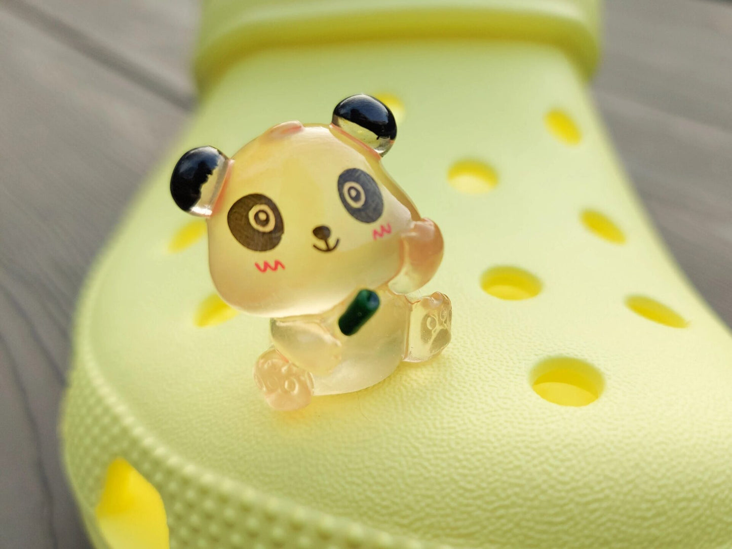 Set of glow in the dark panda shoe charms displayed on a shoe shoe. The charms feature small panda bears in various colors, with a glowing effect. These adorable accessories are designed to light up in the dark.