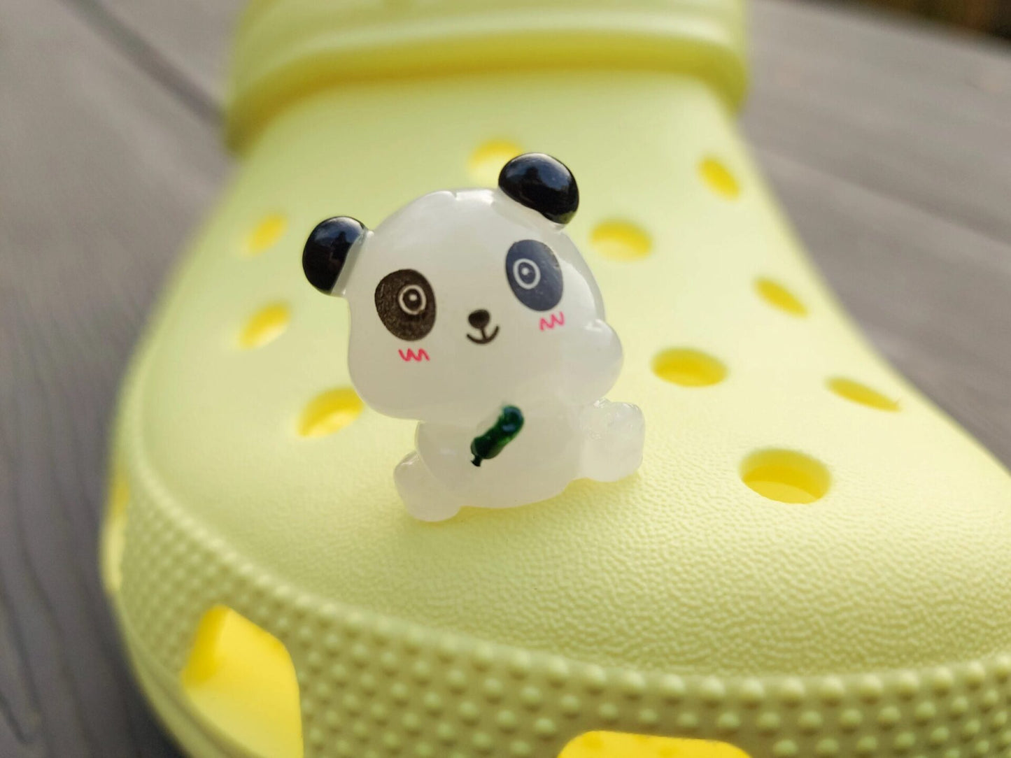 Set of glow in the dark panda shoe charms displayed on a shoe shoe. The charms feature small panda bears in various colors, with a glowing effect. These adorable accessories are designed to light up in the dark.