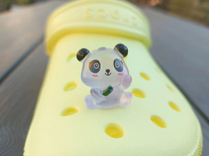 Set of glow in the dark panda shoe charms displayed on a shoe shoe. The charms feature small panda bears in various colors, with a glowing effect. These adorable accessories are designed to light up in the dark.
