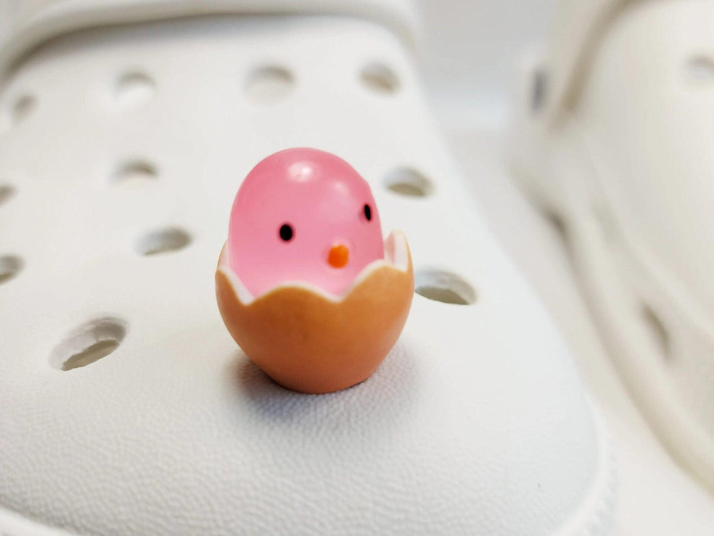A collection of glow-in-the-dark shoe charms featuring adorable baby chicks nestled in colorful egg shells. Each charm showcases a bright chick in a variety of soft, pastel hues, perfect for adding a fun and playful glow to your shoes at night.