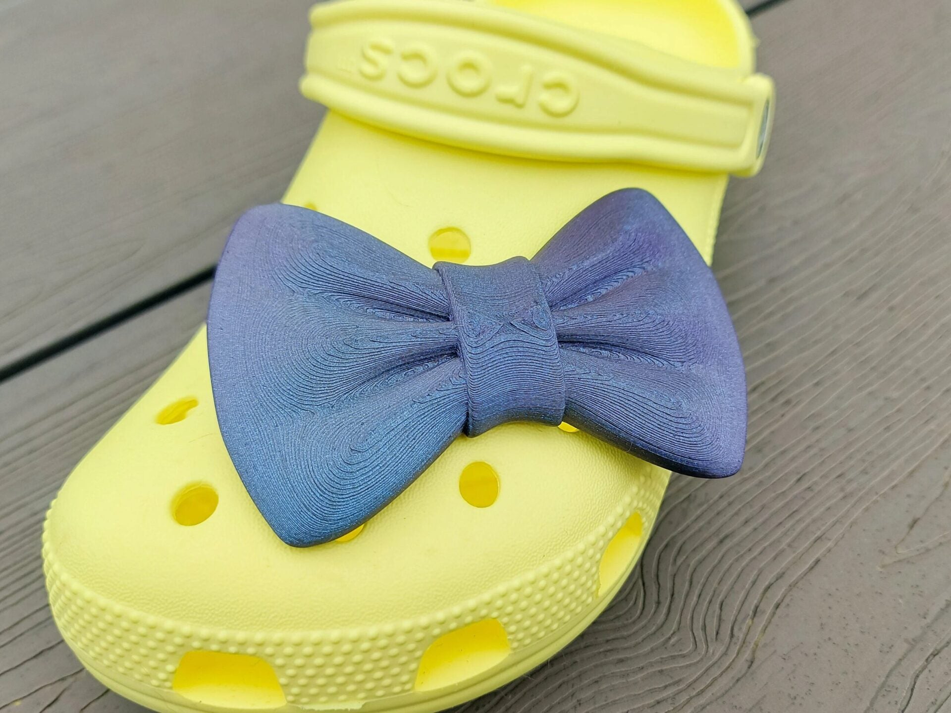 3d-printed bow shoe charms on a pair of shoes shoes. Multiple colors and they have a sparkly glitter.