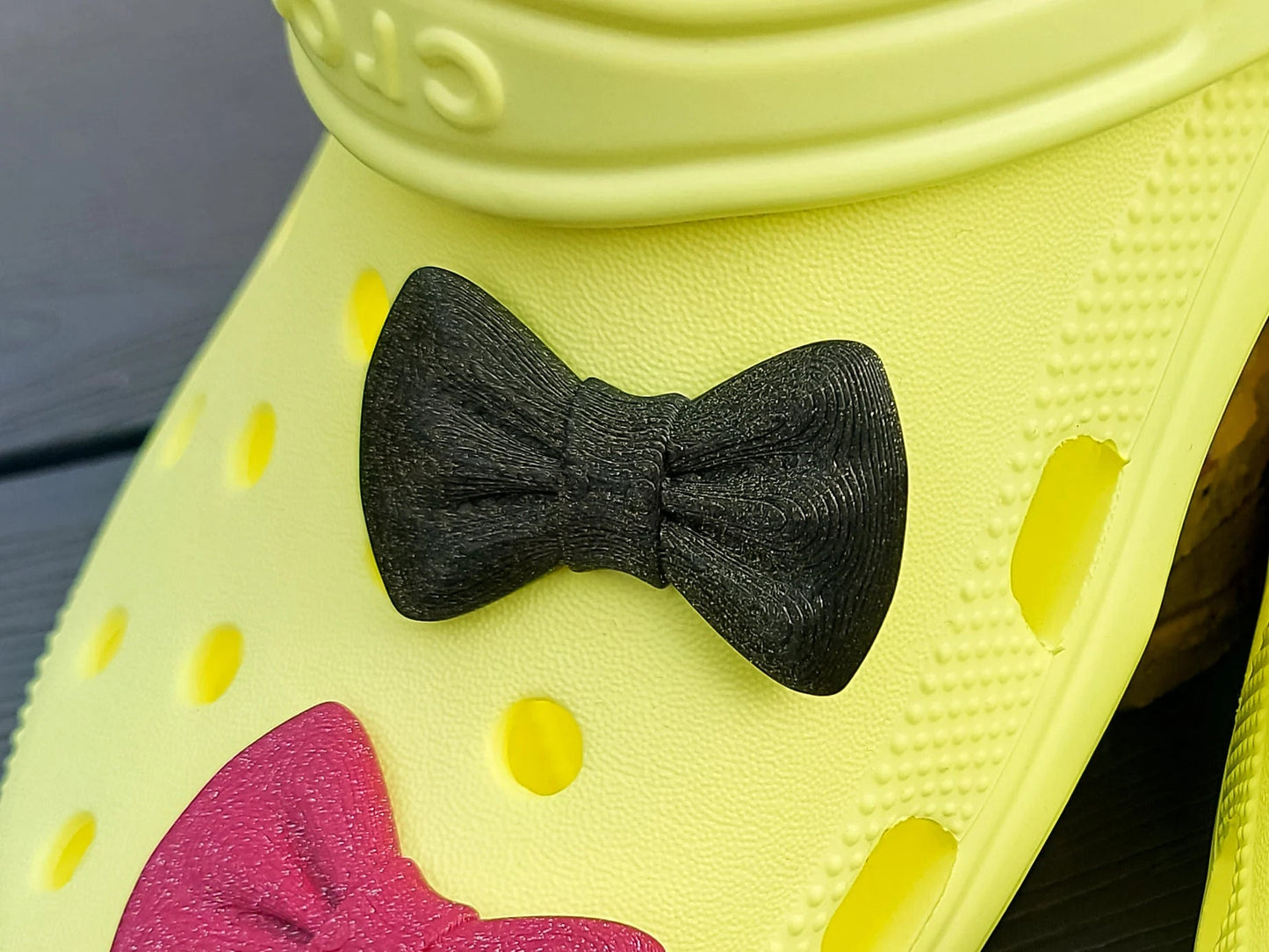 3d-printed bow shoe charms on a pair of shoes shoes. Multiple colors and they have a sparkly glitter.