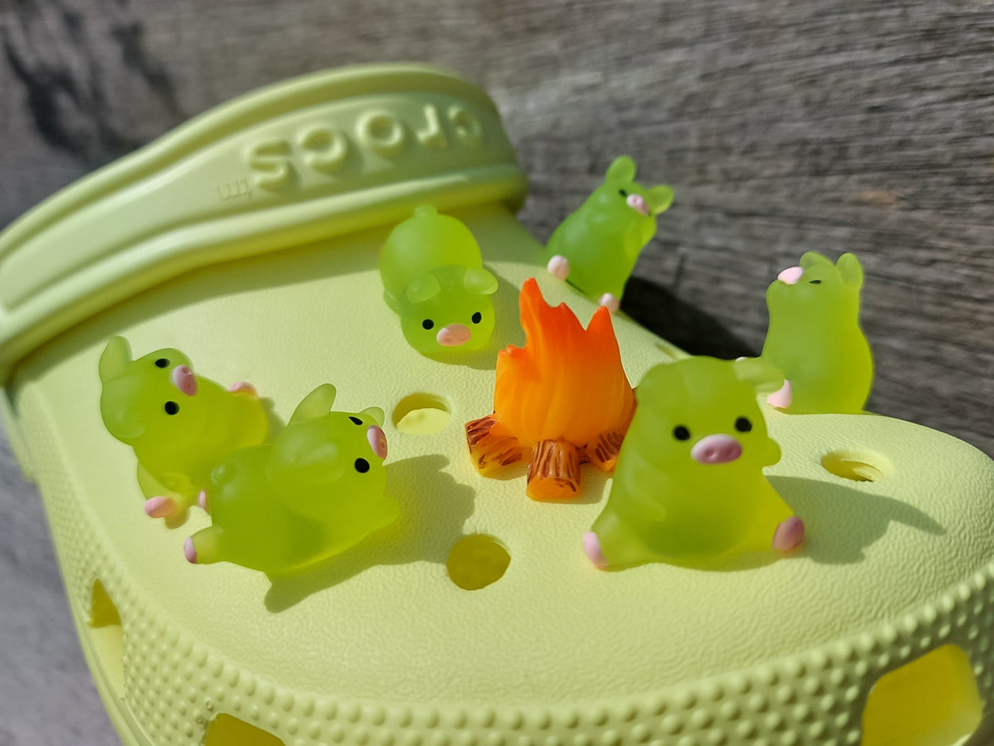 Set of glow-in-the-dark shoe charms featuring adorable pigs around a campfire on a shoe shoe. These playful accessories light up in the dark, adding a unique and whimsical touch to your footwear, perfect for personalizing your shoes.