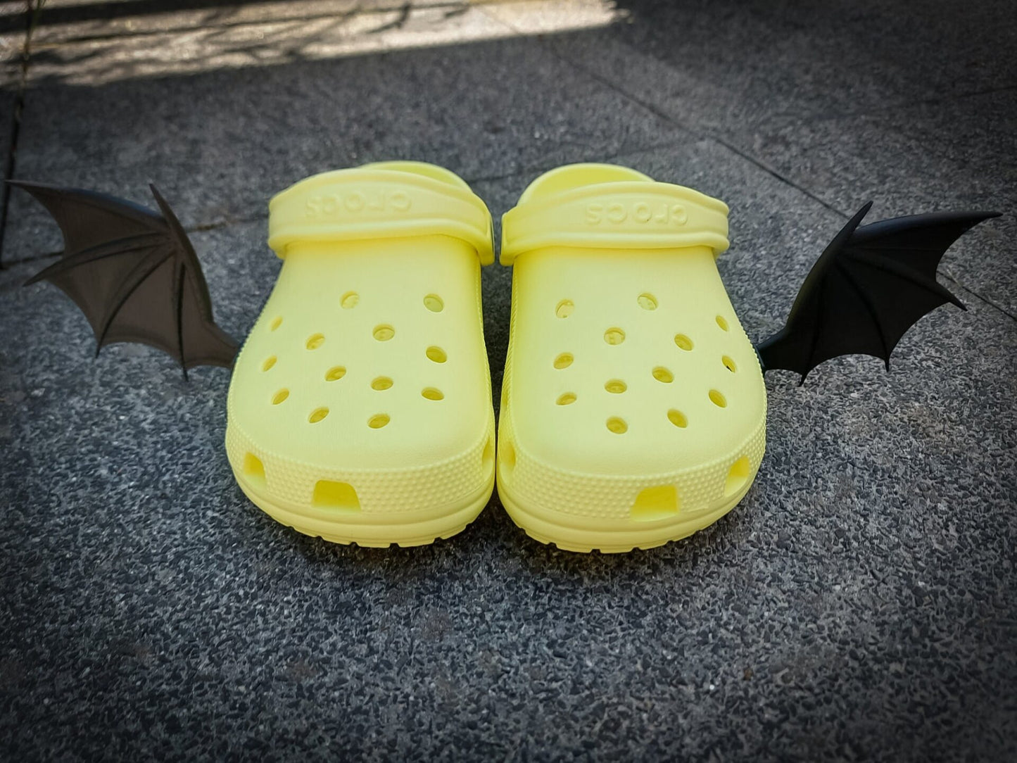 3d-printed bat or dragon wings shoe charms on a pair of shoes shoes. They look halloween themed.