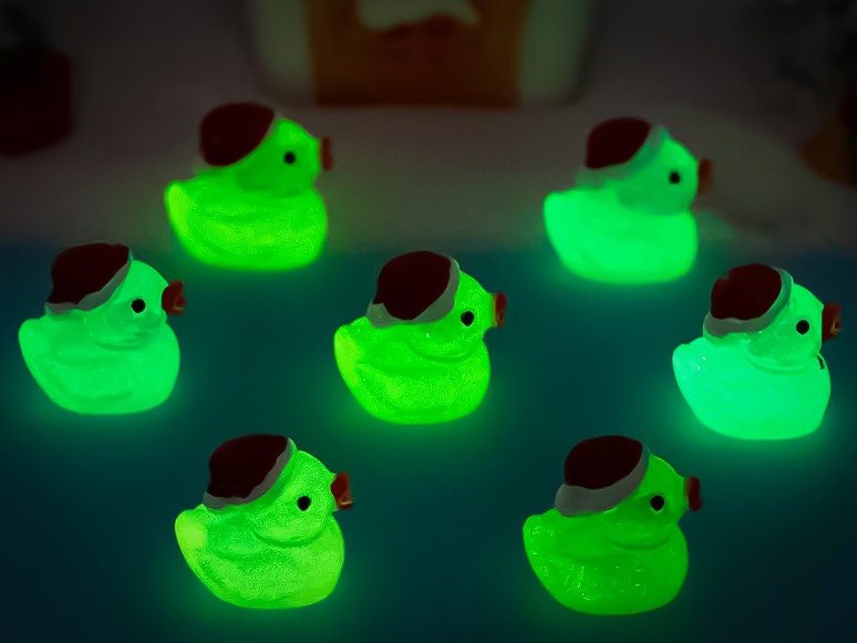 Glow-in-the-dark duck charms wearing Santa hats on a pair of shoes shoes. These festive and luminous accessories add a playful, holiday-themed touch to your footwear, perfect for customizing your shoes with a unique, glowing Christmas spirit.