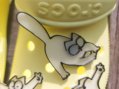Various 3d-printed cartoon cat shoe charms that glow in the dark on a pair of yellow shoes. Each cat has unique features and expressions.