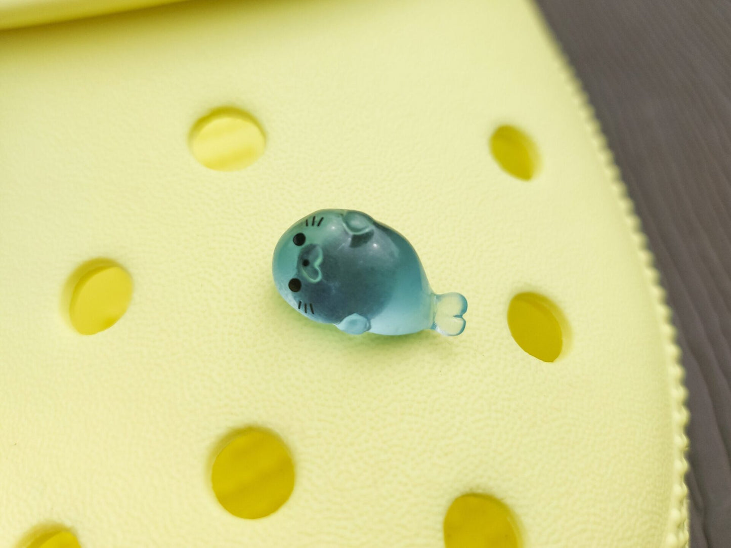Glow in the dark seal shoe charms on a pair of shoes shoes. The seals are made of resin and are each in different playful positions.