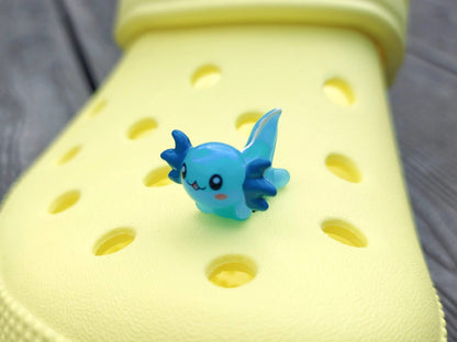 Colorful axolotl charms on a pair of yellow shoes shoes. The axolotls are blue, purple, green, orange, yellow and pink and have cute, smiling faces.