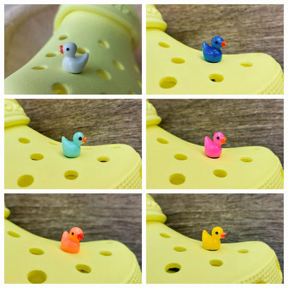 Colorful duck shoe charms on a pair of shoes shoes. The ducks resemble a rubber bath duckie.