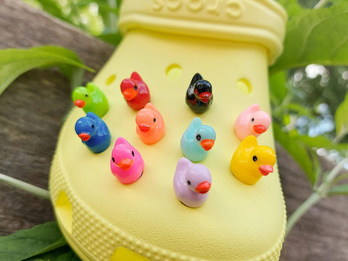 Colorful duck shoe charms on a pair of shoes shoes. The ducks resemble a rubber bath duckie.