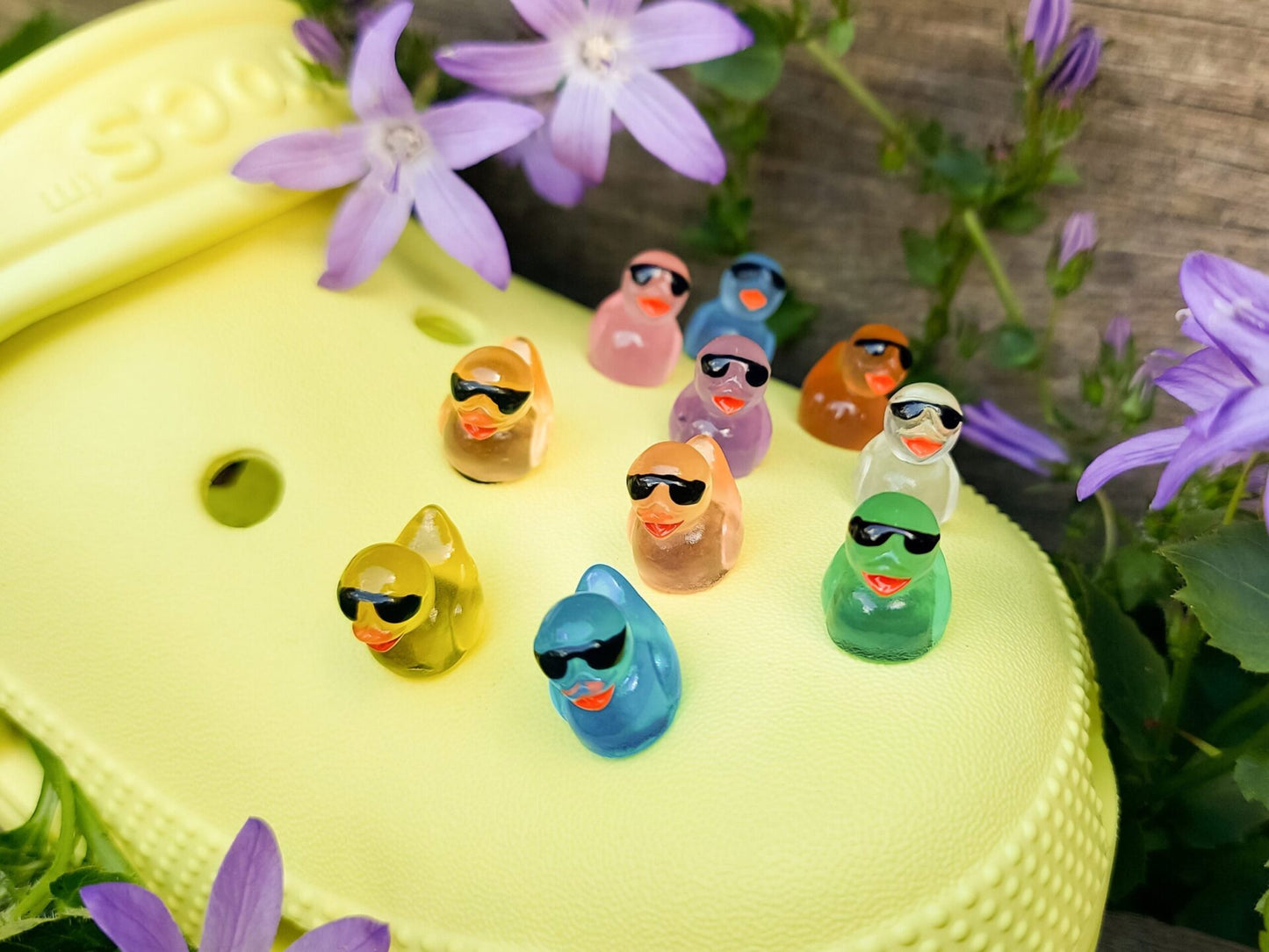 Glow-in-the-dark shoe charms shaped like cool ducks wearing sunglasses. These vibrant ducks come to life in the dark, glowing in neon shades while their tiny black sunglasses add a playful, stylish touch to your shoes.