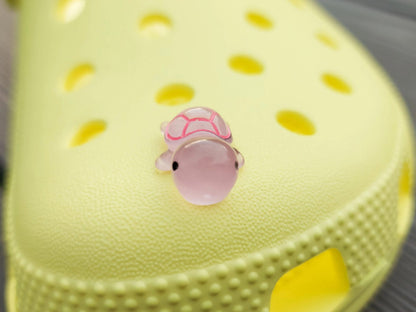 Glow-in-the-dark turtle charms on a shoe shoe. These adorable accessories, featuring detailed shell designs, bring a playful and luminous touch to the footwear, perfect for customizing your shoes with a fun, ocean-inspired look.