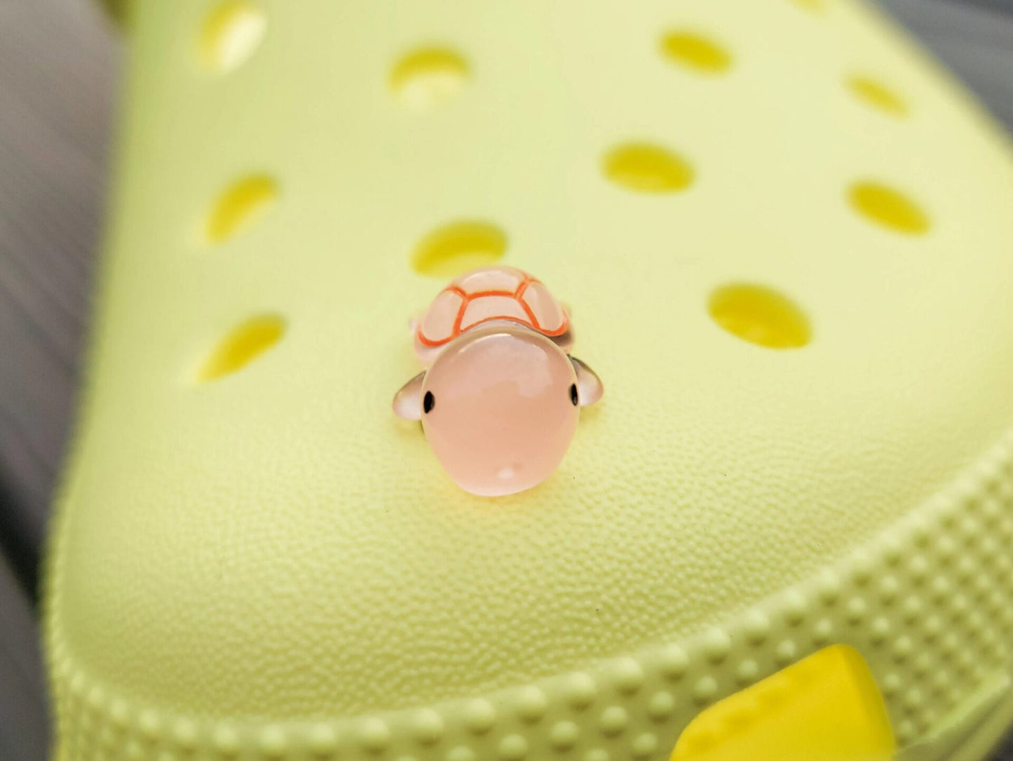 Glow-in-the-dark turtle charms on a shoe shoe. These adorable accessories, featuring detailed shell designs, bring a playful and luminous touch to the footwear, perfect for customizing your shoes with a fun, ocean-inspired look.