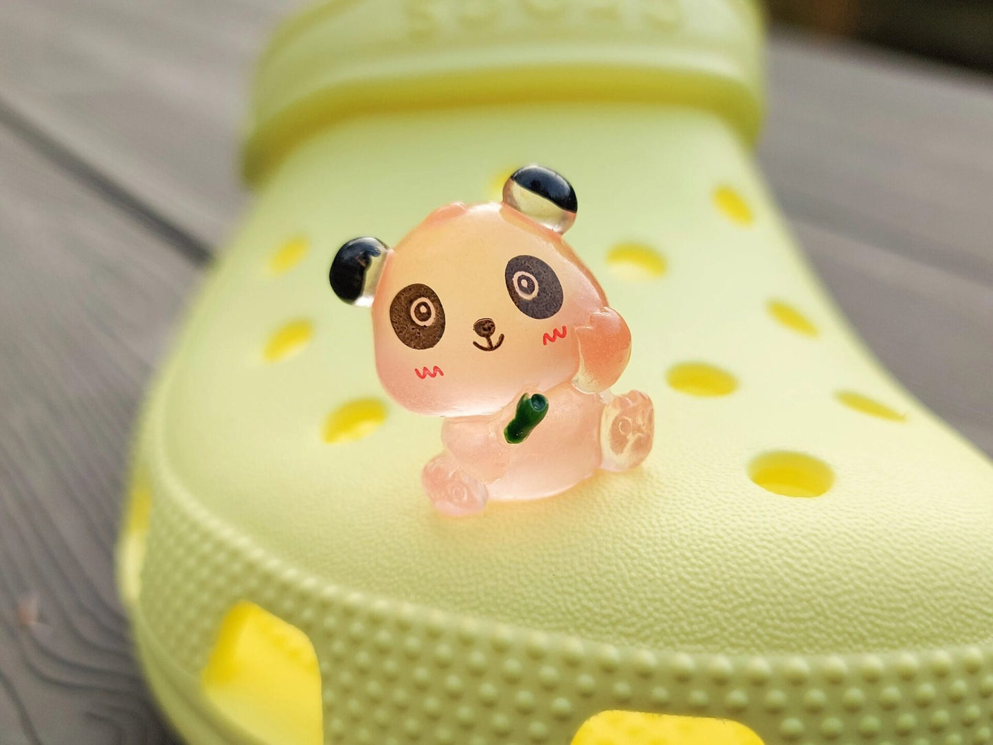Set of glow in the dark panda shoe charms displayed on a shoe shoe. The charms feature small panda bears in various colors, with a glowing effect. These adorable accessories are designed to light up in the dark.