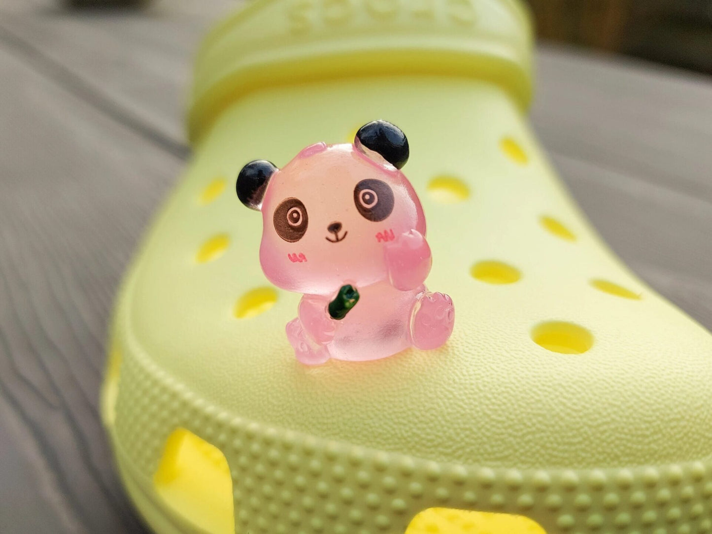 Set of glow in the dark panda shoe charms displayed on a shoe shoe. The charms feature small panda bears in various colors, with a glowing effect. These adorable accessories are designed to light up in the dark.