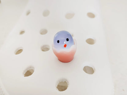 A collection of glow-in-the-dark shoe charms featuring adorable baby chicks nestled in colorful egg shells. Each charm showcases a bright chick in a variety of soft, pastel hues, perfect for adding a fun and playful glow to your shoes at night.