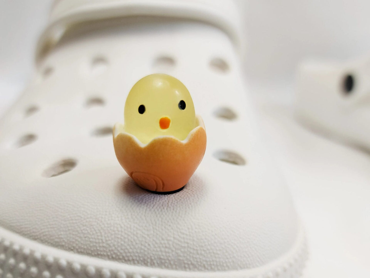 A collection of glow-in-the-dark shoe charms featuring adorable baby chicks nestled in colorful egg shells. Each charm showcases a bright chick in a variety of soft, pastel hues, perfect for adding a fun and playful glow to your shoes at night.