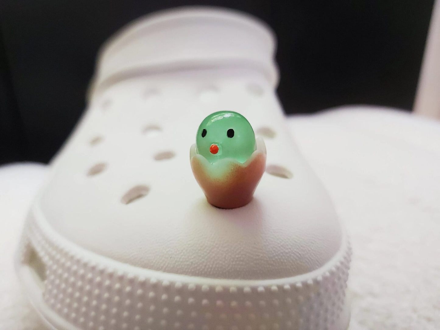 A collection of glow-in-the-dark shoe charms featuring adorable baby chicks nestled in colorful egg shells. Each charm showcases a bright chick in a variety of soft, pastel hues, perfect for adding a fun and playful glow to your shoes at night.