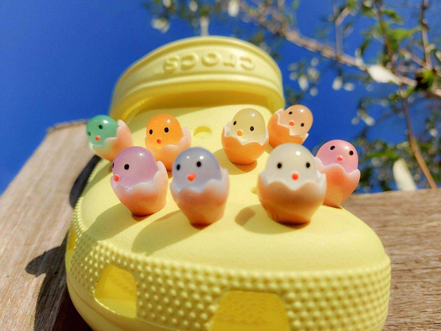 A collection of glow-in-the-dark shoe charms featuring adorable baby chicks nestled in colorful egg shells. Each charm showcases a bright chick in a variety of soft, pastel hues, perfect for adding a fun and playful glow to your shoes at night.