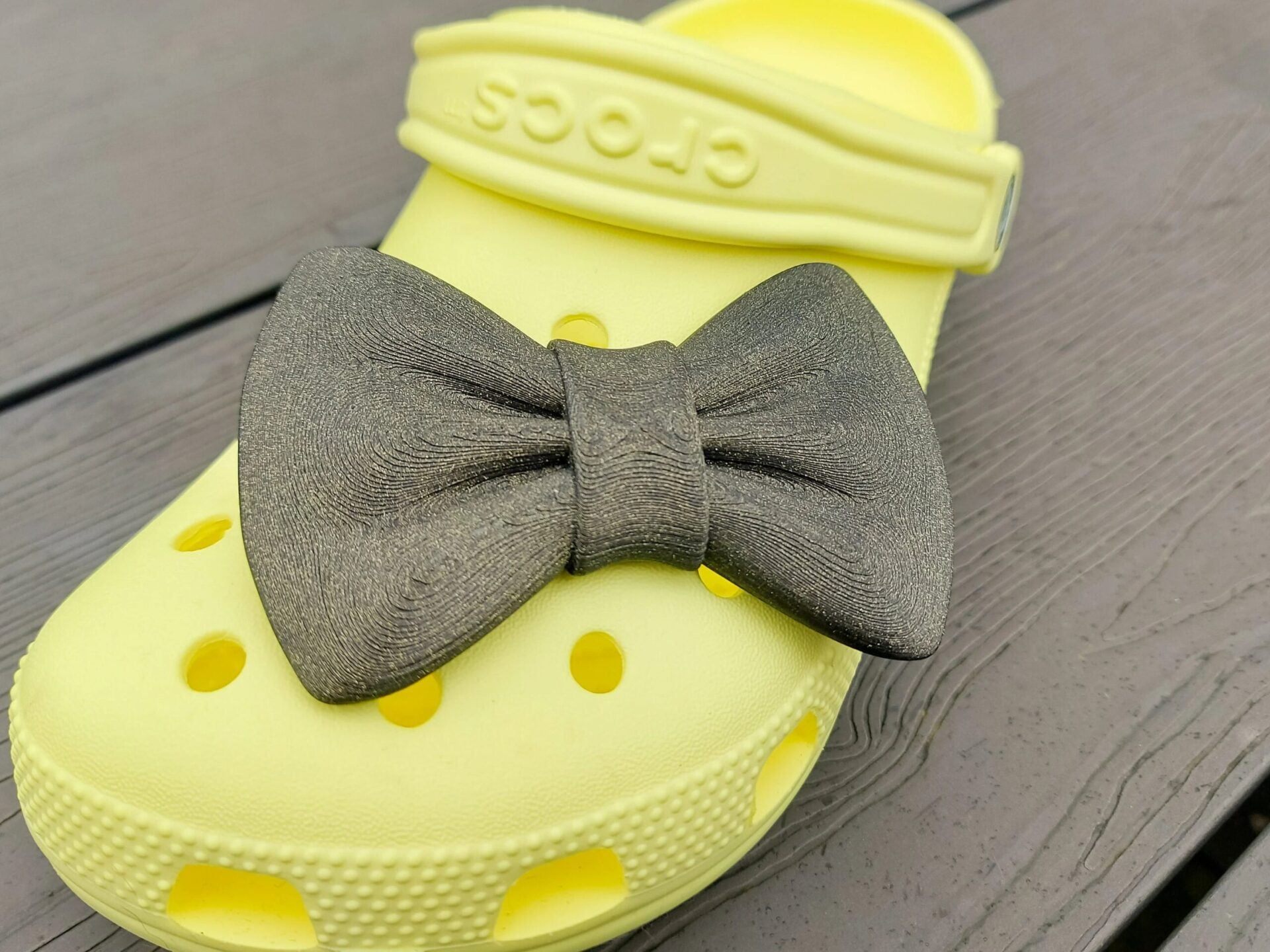 3d-printed bow shoe charms on a pair of shoes shoes. Multiple colors and they have a sparkly glitter.