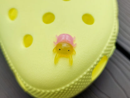 A vibrant collection of beetle-themed shoe charms decorates a yellow shoes shoe. The charms feature detailed, multicolored beetles in various shades, adding a playful yet nature-inspired vibe to the footwear.