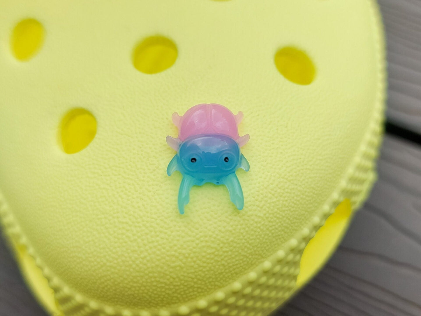 A vibrant collection of beetle-themed shoe charms decorates a yellow shoes shoe. The charms feature detailed, multicolored beetles in various shades, adding a playful yet nature-inspired vibe to the footwear.