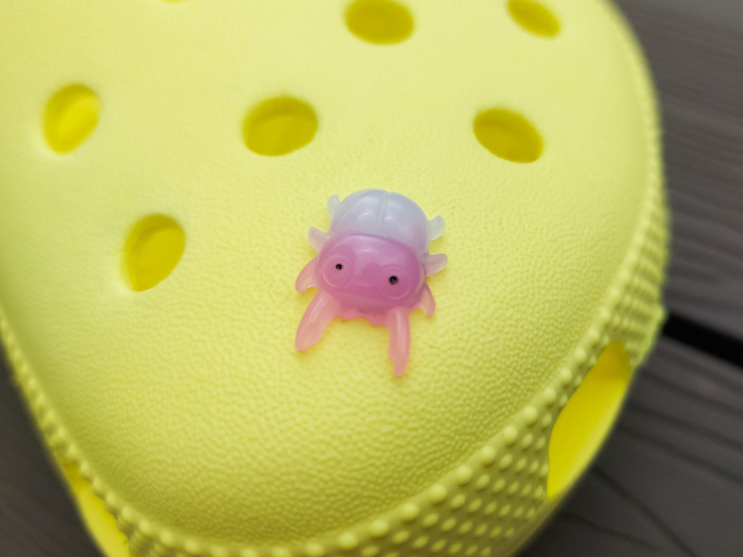 A vibrant collection of beetle-themed shoe charms decorates a yellow shoes shoe. The charms feature detailed, multicolored beetles in various shades, adding a playful yet nature-inspired vibe to the footwear.