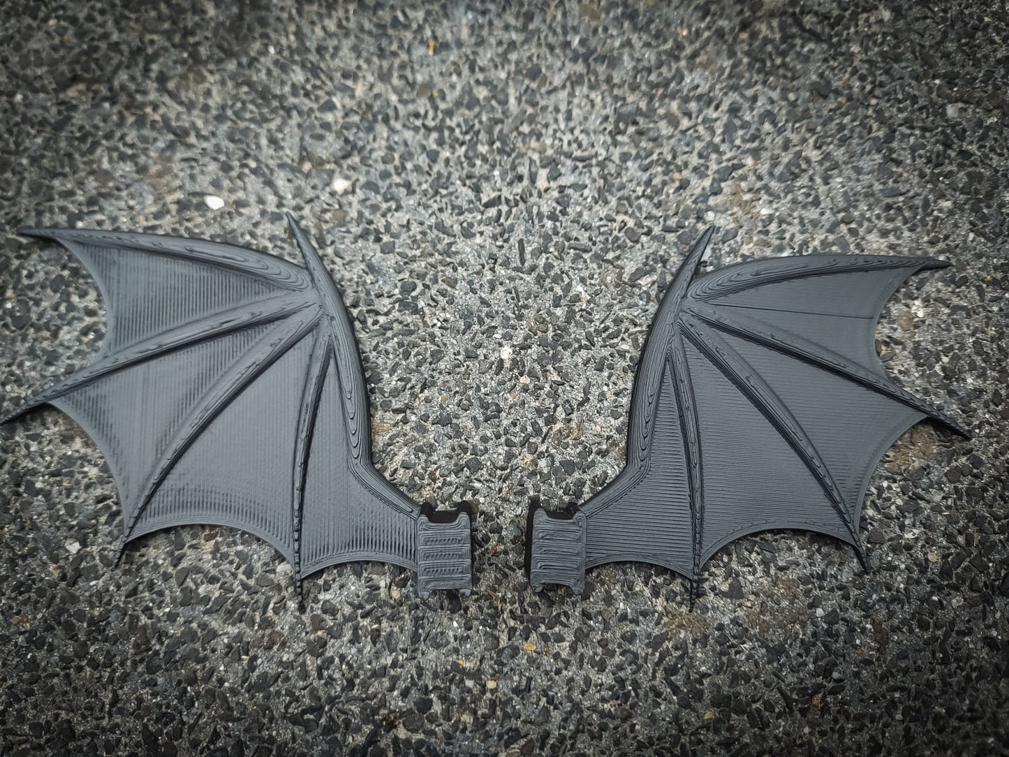 3d-printed bat or dragon wings shoe charms on a pair of shoes shoes. They look halloween themed.