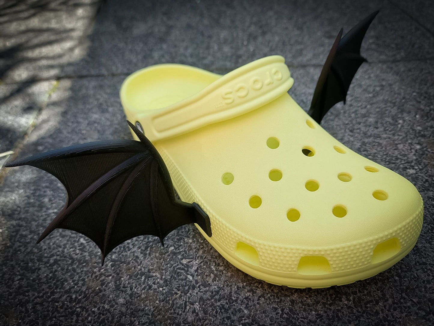 3d-printed bat or dragon wings shoe charms on a pair of shoes shoes. They look halloween themed.