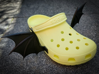 3d-printed bat or dragon wings shoe charms on a pair of shoes shoes. They look halloween themed.