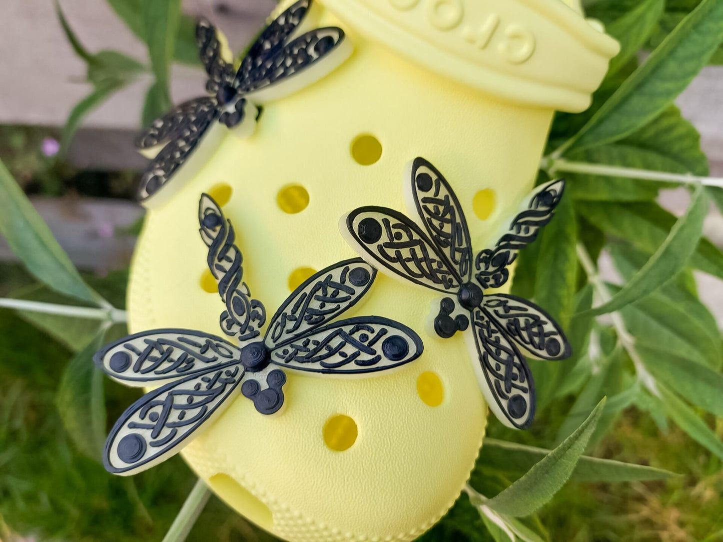 3D-printed glow-in-the-dark dragonfly charm with a Celtic weave pattern on a shoe shoe. The intricate design adds a whimsical and enchanting touch to the footwear, perfect for day or night style.